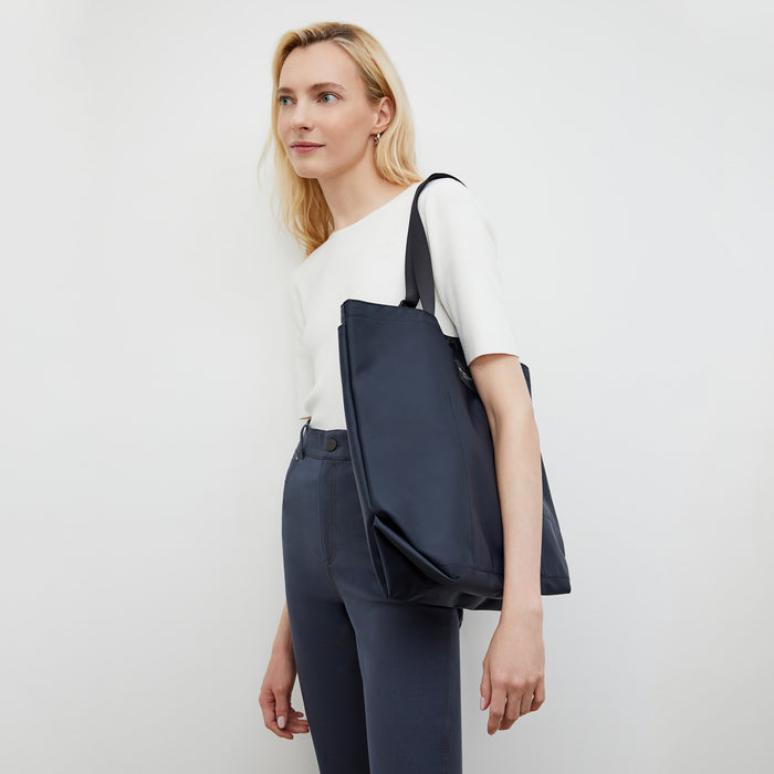 Side image of a woman wearing the Bags in Progress x MM Carry All Tote  in Navy