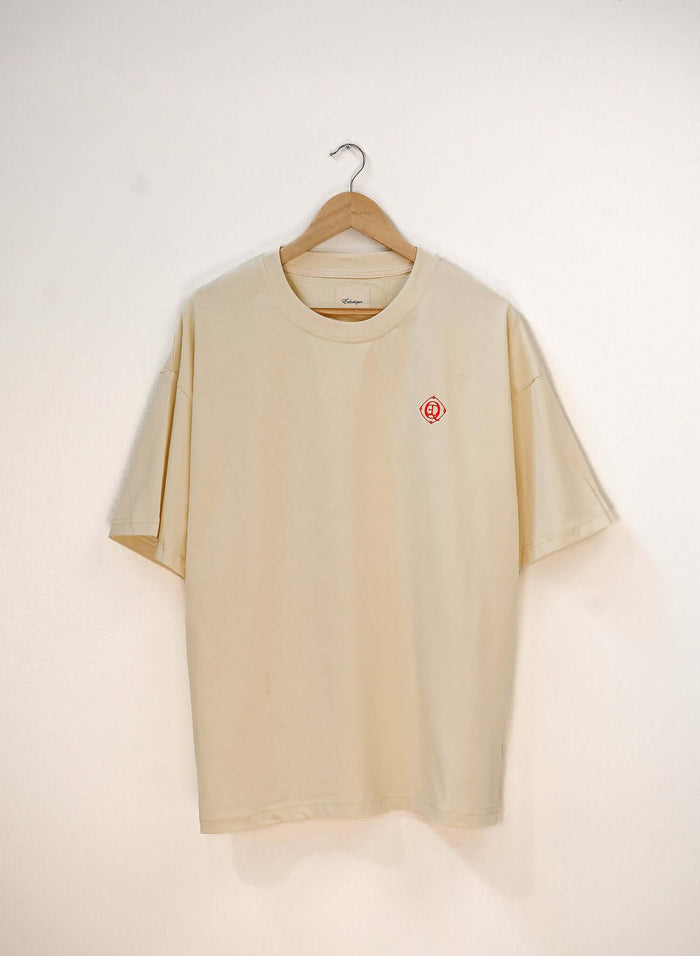 Monogram embroidered cotton t-shirt in French vanilla hanging on a wooden hanger.
