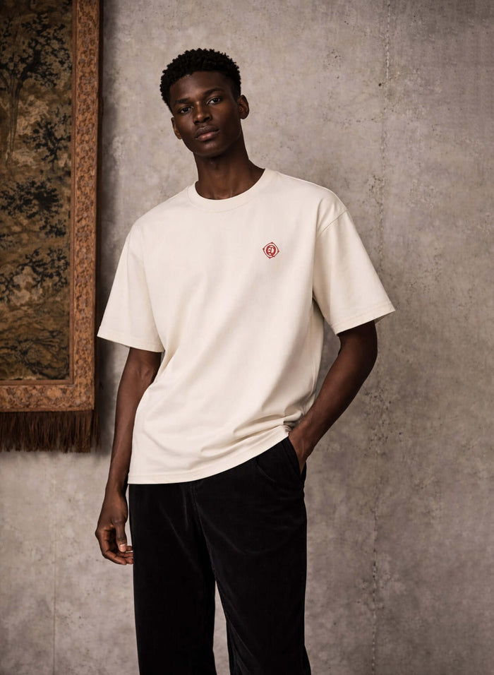 Monogram embroidered cotton t-shirt in French vanilla worn by model, featuring embroidered logo on left chest.
