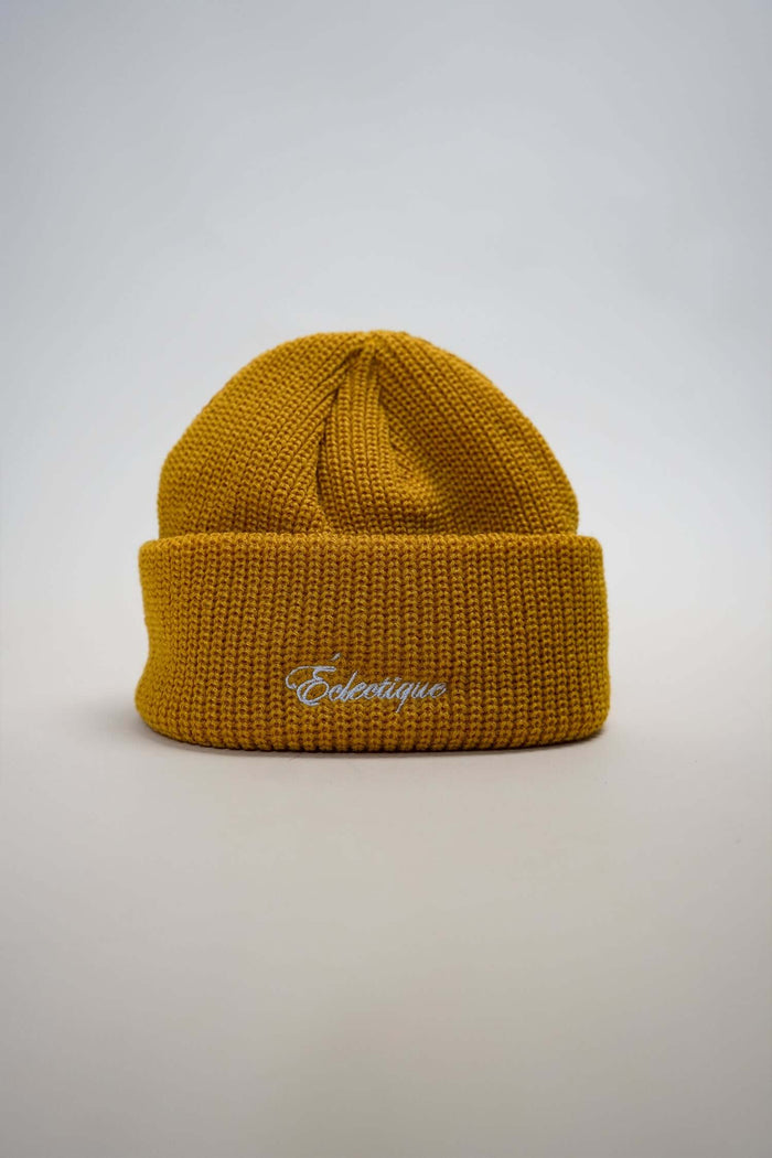 Mustard fisherman beanie from Éclectique with white logo embroidery and classic cuffed design.