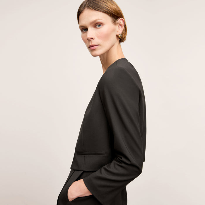 Side image of a woman standing wearing the Neale jacket in black