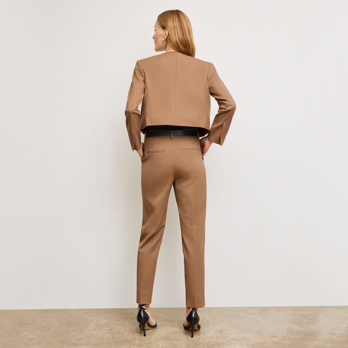 back image of a woman standing wearing the Neale jacket in camel