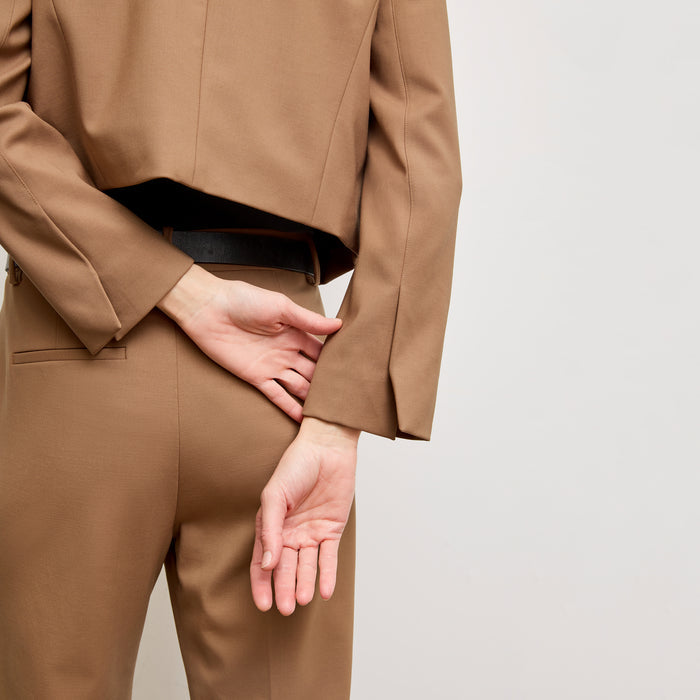 back image of a woman standing wearing the Neale jacket in camel