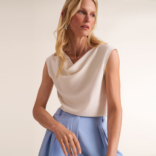 Woman wearing a cowl neck sleeveless top with light blue pants | Lead