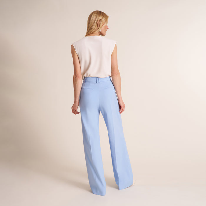 Woman wearing a cowl neck sleeveless top with light blue pants