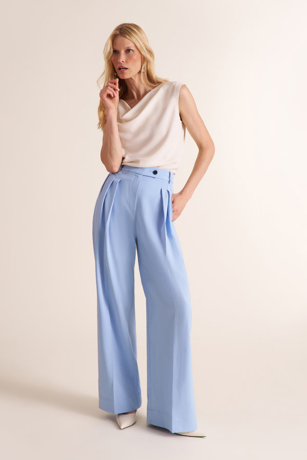 Woman wearing a cowl neck sleeveless top with light blue pants | Exclude