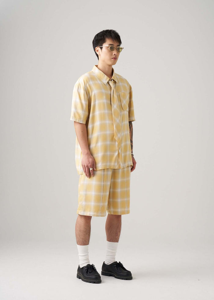 Ombre plaid shirt in yellow styled with matching shorts for a trendy summer look.