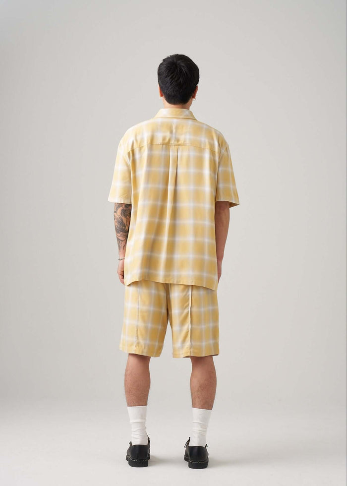 Man wearing an ombre plaid shirt in yellow, showcasing the back view and its comfortable fit.