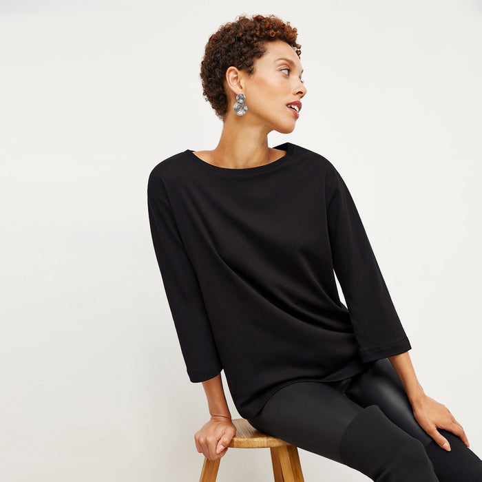 Front image of a woman sitting wearing the Owen T-Shirt in Black