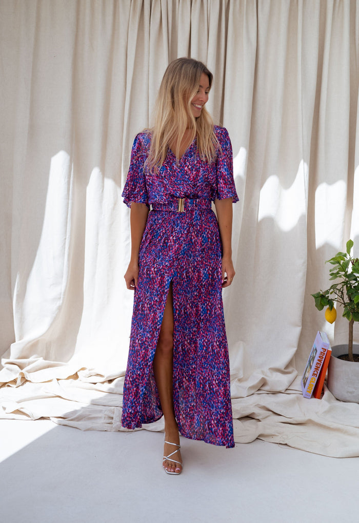 Woman wearing blue and pink wrap maxi dress with belt