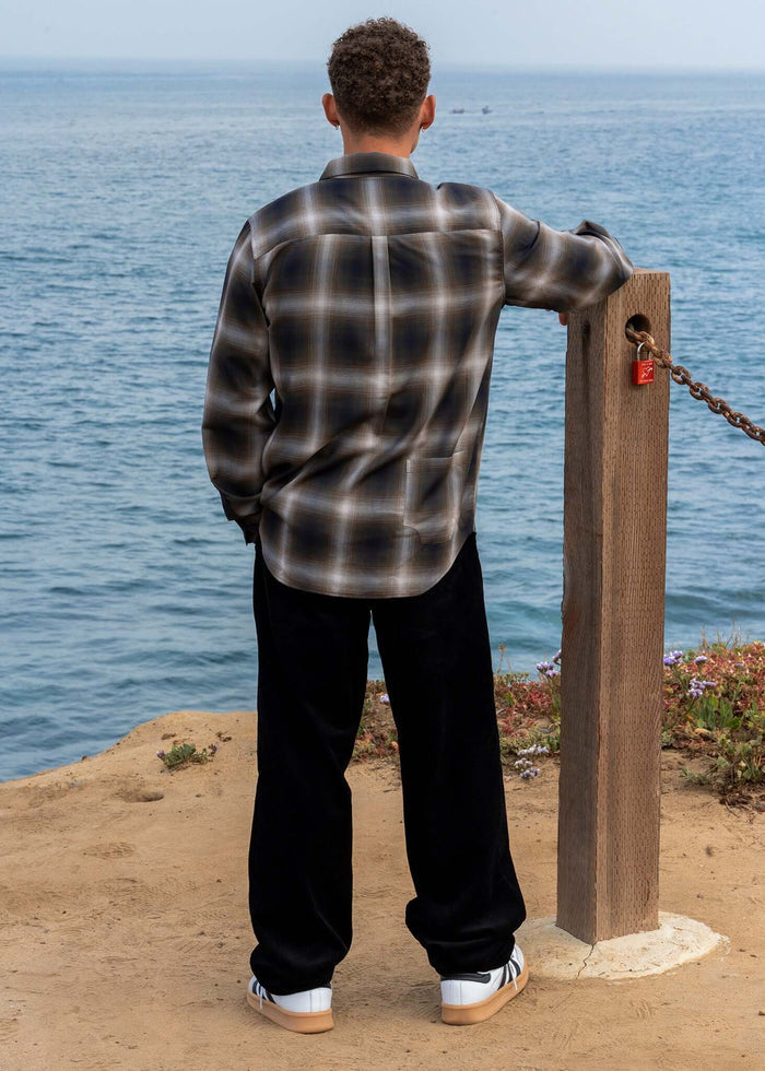 Man wearing a Plaid Cotton Button-Up Shirt, standing by the ocean with a casual style.