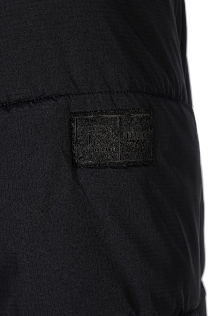 Detail of a black ripstop jacket featuring a logo badge.