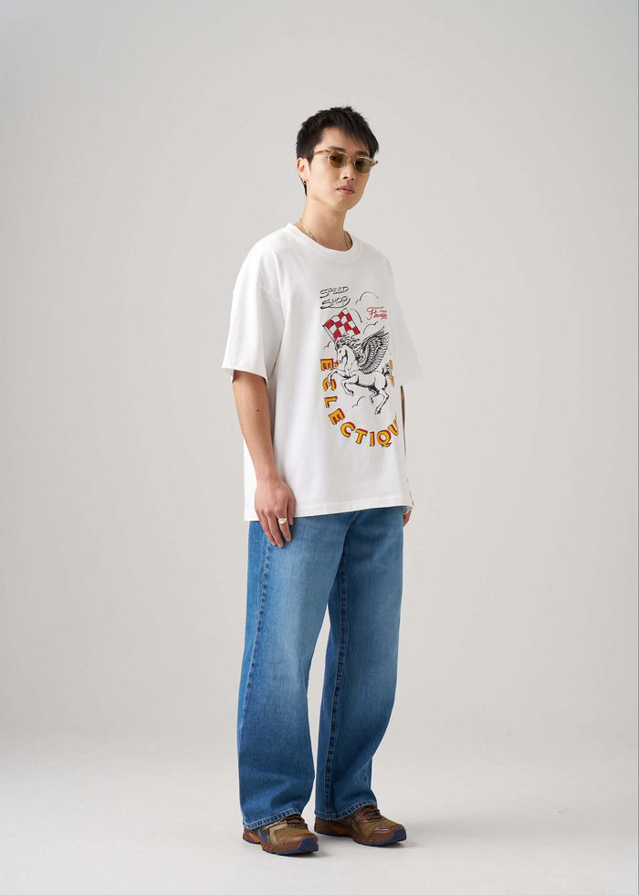 Model wearing a Racing Graphic T-shirt from Éclectique Speed Shop, paired with blue jeans and sunglasses.