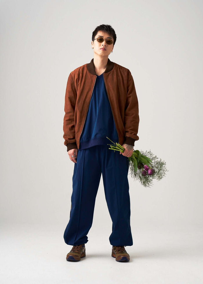 Reversible Windbreaker Pants with a brown bomber jacket and holding flowers.