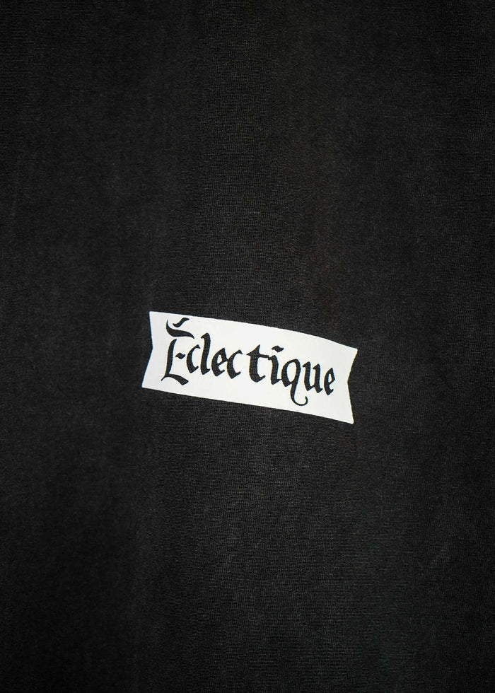 Close-up of Éclectique label on a black fabric, showcasing the brand name in stylish typography for rockets graphic t-shirt