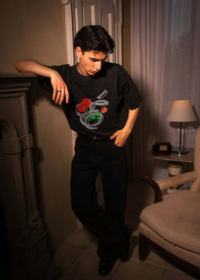 Model wearing Éclectique Rose Graphic T-Shirt with three detailed roses design in a stylish urban setting.