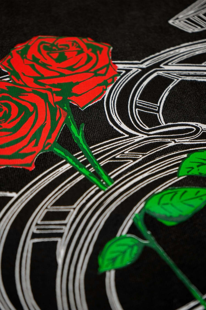 Close-up of the design on an Éclectique Rose Graphic T-Shirt featuring red roses and intricate details on a black background.