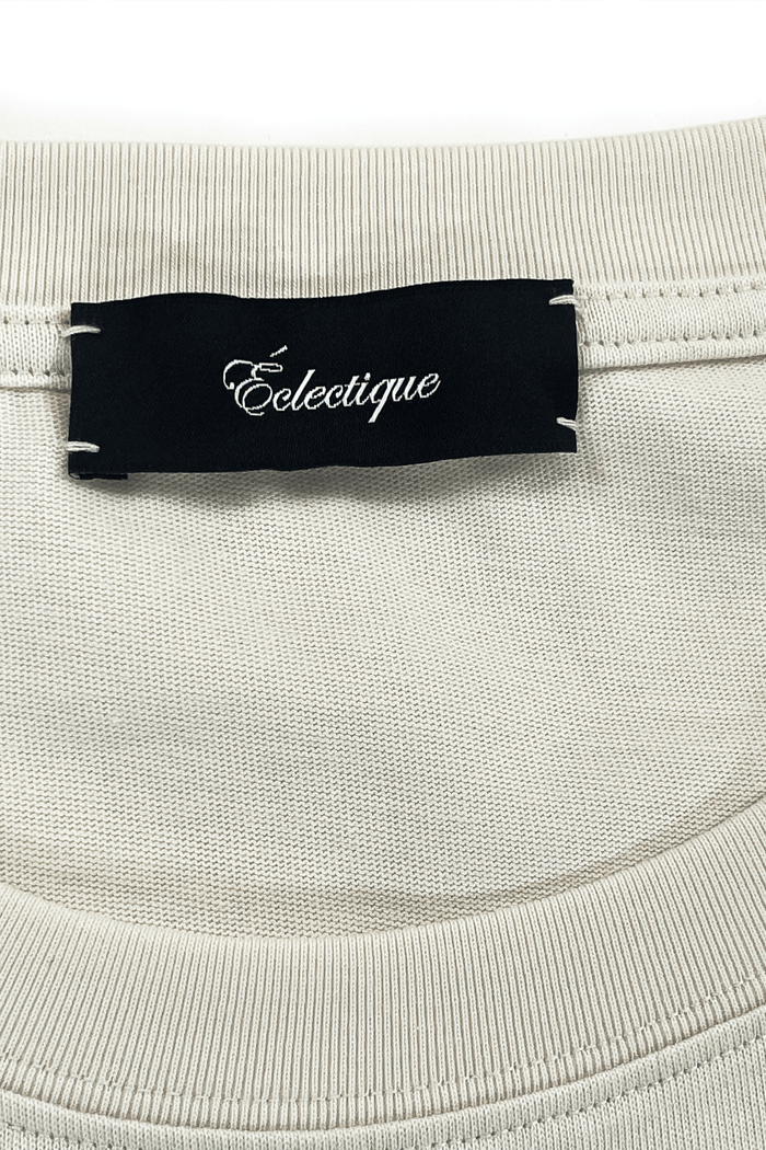 Label of Éclectique on running graphic t-shirt showcasing the brand name prominently on a light fabric.