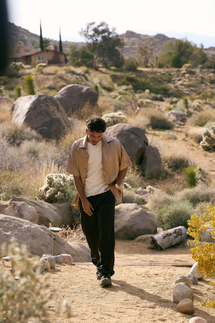 beige silk bowling shirt paired with relaxed trousers in desert setting