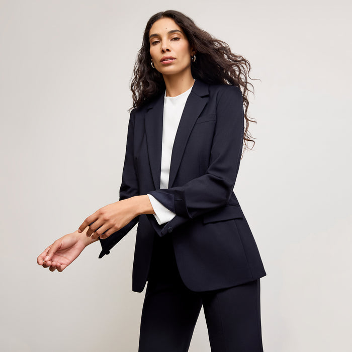 front image of a woman sitting wearing the yiyan petite blazer in galaxy blue | Exclude