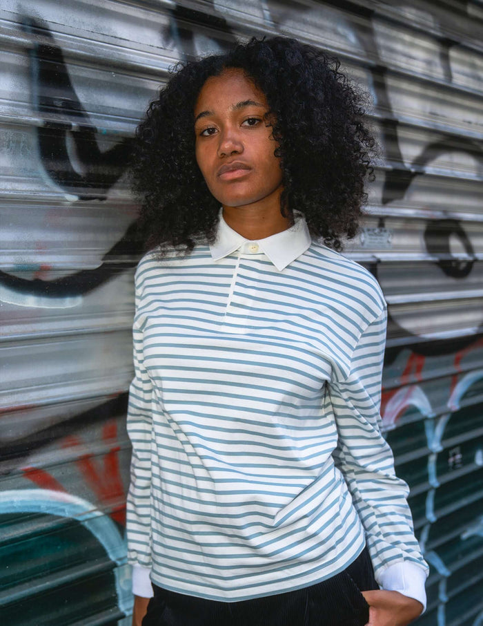 Striped long sleeve rugby shirt featuring blue-grey horizontal stripes and a white collar, worn by a model.