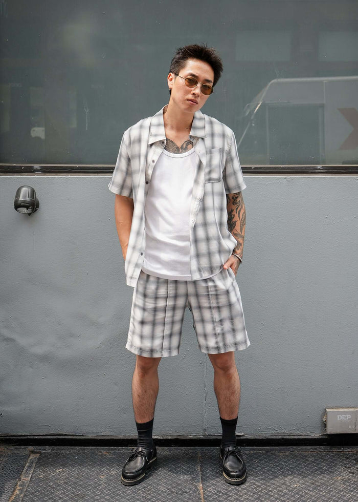 Model wearing monotone plaid shorts with matching shirt, showcasing stylish and casual summer outfit.