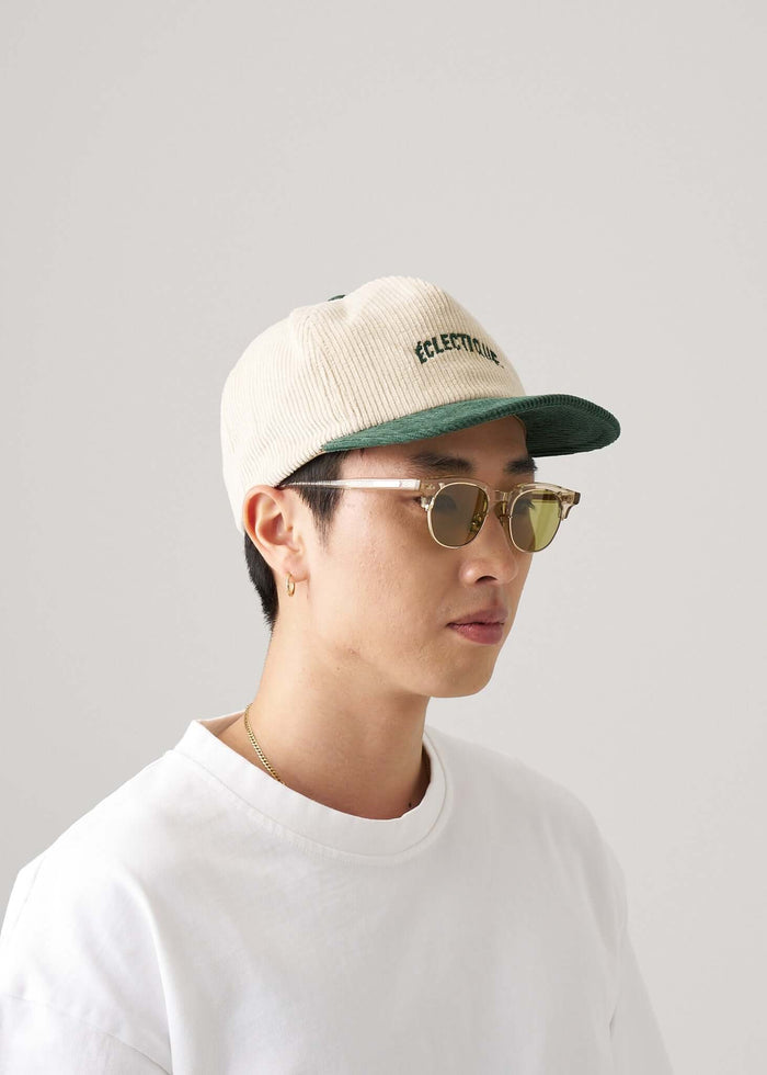 Two tone snapback hat in green and natural worn by a person with sunglasses.
