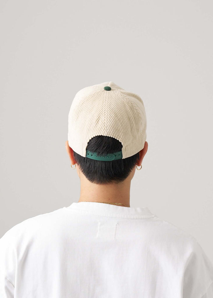 Back view of a person wearing a two tone snapback hat in green and natural.