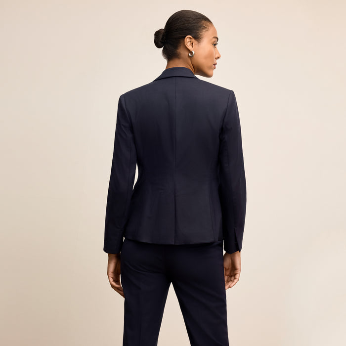 Woman wearing a navy blue suit on a beige background