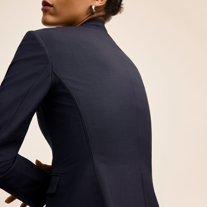 Navy blue suit jacket worn by a person on a beige background