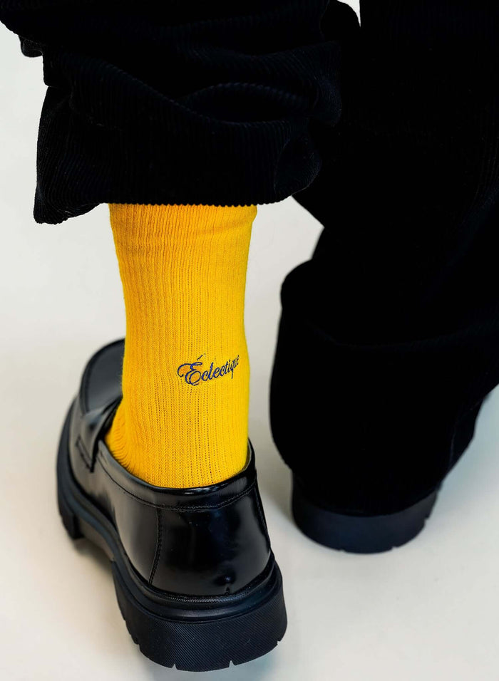 Close-up of yellow crew socks in Spectra worn with black shoes, showcasing their vibrant color and comfortable fit.