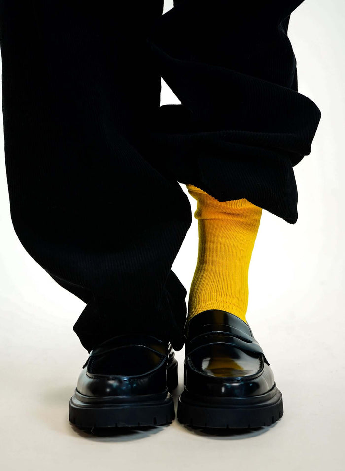 Yellow crew socks paired with black loafers and pants, showcasing a stylish contrast.